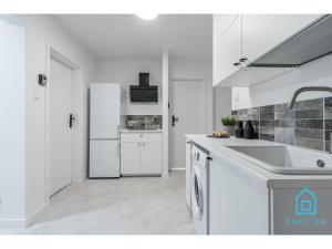 格但斯克Lavender Room的白色的厨房配有水槽和冰箱