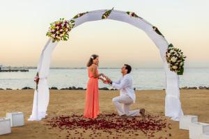 赫尔格达沙漠玫瑰度假村 的海滩上拱门下的新娘和新郎跳舞