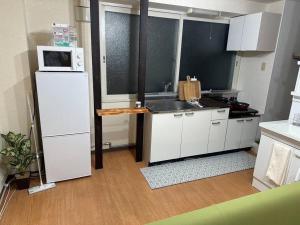 札幌Monster lodge 札幌的厨房配有白色冰箱和微波炉