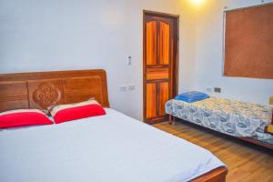 CabuyaoCasa de madera the wooden house的一间卧室配有一张带两个红色枕头的床