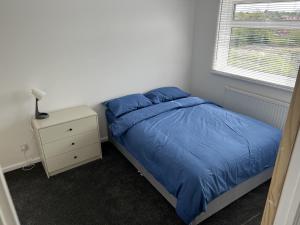 莱顿巴泽德Charming 3-Bed House in Leighton Buzzard的一间卧室配有蓝色的床和床头柜