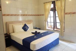 库塔LH - Norm House的一间卧室配有一张带蓝色和白色床单的床和窗户。