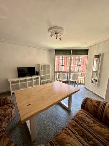 塞维利亚Apartamento en Sevilla的客厅配有木桌和电视。