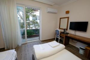 安塔利亚Venüs Hotel的酒店客房配有一张床、一张书桌和一台电视。
