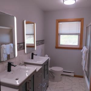 迪格比码头边套房宾馆的白色的浴室设有2个盥洗盆和1个卫生间。