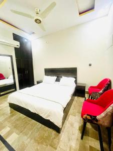 卡拉奇Hotel Highway Link的一间卧室配有白色的床和两张红色椅子