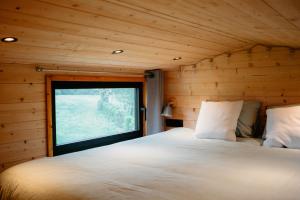 VerlaineBerta Tiny house的木制客房的一张床位,设有窗户