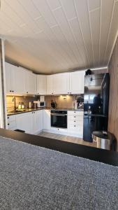 SorreisaCosy cabin in North-Norway, Nearby Senja.的厨房配有白色橱柜和黑色冰箱。