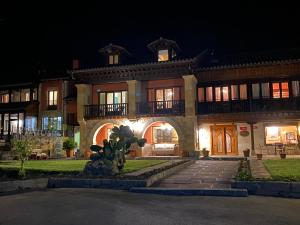 Cabezón de LiébanaHotel Finca Malvasia的一座大房子,在晚上,前面有雕像