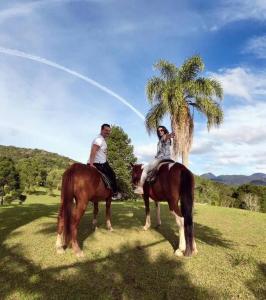 Represa CapivariApartamento completo em Resort的两个人在棕榈树旁边骑马