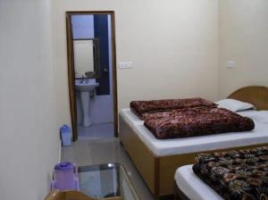 巴德里纳特OM Kutir Badrinath Dham的配有镜子和水槽的客房内的两张床
