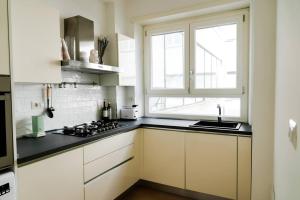 罗马ophelia apartment的厨房配有白色橱柜、水槽和窗户。