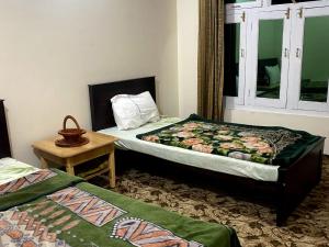KhapaluMoon Light Guest House Khaplu的一间卧室设有两张床、一张桌子和一个窗口