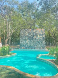 皮雷诺波利斯Sítio Quinta da Mata Chalé Amarelo的一座拥有石墙和蓝色海水的游泳池