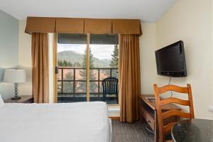 惠斯勒Cascade Lodge的酒店客房设有一张床和一个大窗户