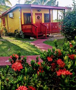圣伊格纳西奥Garden Cottage的前面有鲜花的黄色和红色房子