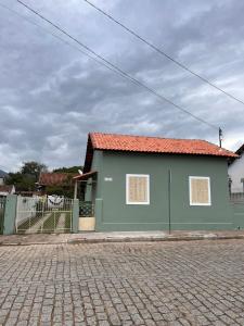 帕萨夸特鲁Casinha Verde的街道上一座绿色建筑,有红色屋顶