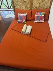 爱妮岛HIRAYA Camp Site - FREE use of SCOOTER for NIPA HUTS的一张带两个枕头的床和两条毛巾