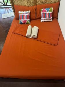 爱妮岛HIRAYA Camp Site - FREE use of SCOOTER for NIPA HUTS的橙色的床,带两条毛巾和枕头