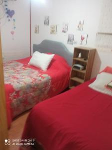 奇廉Hostal Familiar 2.0的红色床单的客房内的两张床