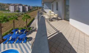 阿尔巴·阿德里亚蒂卡Residence il Girasole 1的阳台配有蓝色椅子和带遮阳伞的桌子。