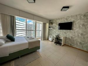 巴西利亚Flat Saint Moritz Brasília Hotel的一间卧室配有一张床、一张书桌和一台电视