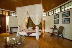 长滩岛Mandala Spa & Resort Villas的一间卧室配有一张带玻璃桌的天蓬床