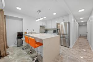 纽约Upper East Side Luxury 3BR 2B的一间厨房,配有白色橱柜和一个带橙色椅子的岛屿