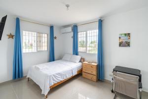圣多明各Casa cerca SDQ & Bus Caribe tours的一间卧室配有蓝色窗帘、一张床和一张书桌