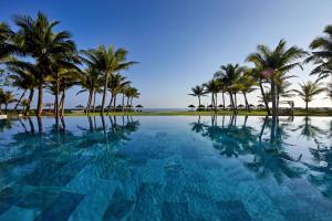 会安Wyndham Hoi An Royal Beachfront Resort & Villas的棕榈树和海洋的游泳池