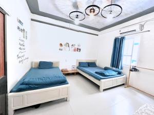 吉婆岛Domik Homestay - Cát Bà的配有蓝色床单的客房内的两张床
