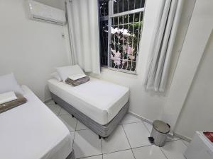 里约热内卢Quarto Privativo em Condominio的白色的客房设有两张床和窗户。