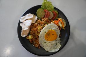 SekongkangBalong Balong Surf Bungalows & Restaurant的黑盘食物,有鸡蛋和蔬菜