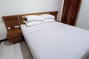 KlatenOYO 93885 D'harjo Guesthouse的一张带白色床单和枕头的床