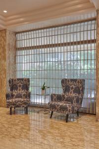孟买Regent Hotel Andheri的带窗户的客房内配有两把椅子和一张桌子