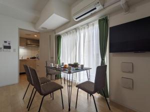 大阪ESLEAD HOTEL Namba South Ⅱ的一间带桌椅和电视的用餐室