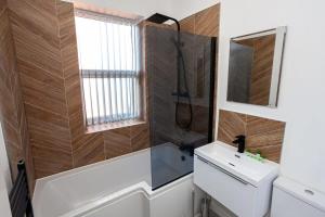 博尔顿Modern 2 Bedroom Apartment in Bolton的一间带水槽、淋浴和镜子的浴室