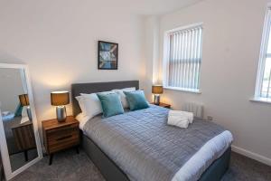 博尔顿Modern 2 Bedroom Apartment in Bolton的一间卧室配有一张带两盏灯和镜子的床