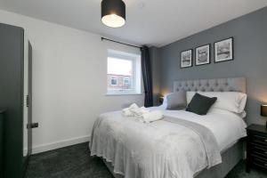 沃勒西Stunning 2 Bedroom Apartment in Wallasey的一间卧室配有一张带白色床单的床和一扇窗户。