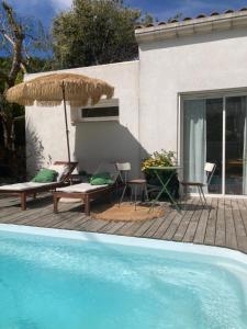 滨海萨纳里Maison d hôtes LA VILLA MADELEINE的一个带遮阳伞和游泳池的庭院