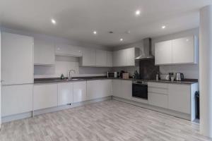 利物浦Modern 2 Bedroom Apartment in Liverpool的白色的厨房配有白色橱柜和电器