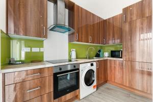 沃金Lovely 1 Bedroom Apartment in Woking Centre的厨房配有木制橱柜、洗衣机和烘干机