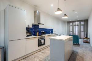 唐克斯特Budget 1 Bed Apartment in Central Doncaster的一间大厨房,配有白色橱柜和蓝色瓷砖