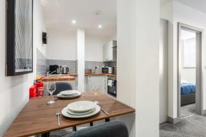 利兹Smart 1 Bedroom Apartment in Leeds的厨房以及带木桌和椅子的用餐室。