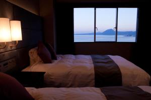 别府Grand Mercure Beppu Bay Resort & Spa的一间卧室设有两张床和大窗户