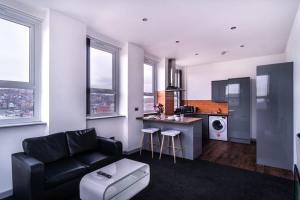 布莱克本Contemporary 1 Bed Apartment in Central Blackburn的一间带黑色沙发的客厅和一间厨房