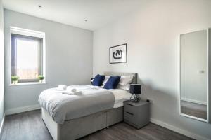 锡福斯Modern & Spacious 2 Bed Apartment in Waterloo Liverpool的一间卧室配有一张带蓝色枕头的床和一扇窗户。