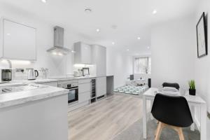 纽伯里Modern 1 Bedroom Apartment in Central Newbury的白色的厨房配有书桌和桌子