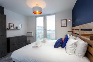 曼彻斯特Stunning 2 Bed Flat 5min to Old Trafford Stadium的一间卧室配有一张带白色和蓝色枕头的大床