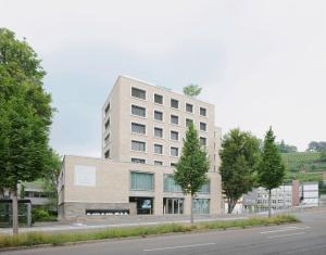 埃斯林根MAVO Hospitality by Büroma Apart Apartmentvermietung GmbH Esslingen的一座高大的白色建筑,前面有树木